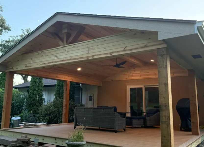 Covered deck with gabled cedar roof, recessed lighting and patio furniture