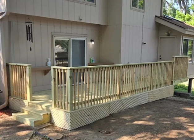 Cedar deck with wood railing, lattice skirting and low steps beside a two story home