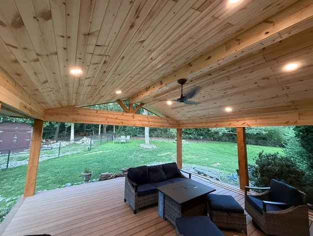 Interior view of a covered deck with tongue and groove cedar ceiling, ceiling fan and lounge seating