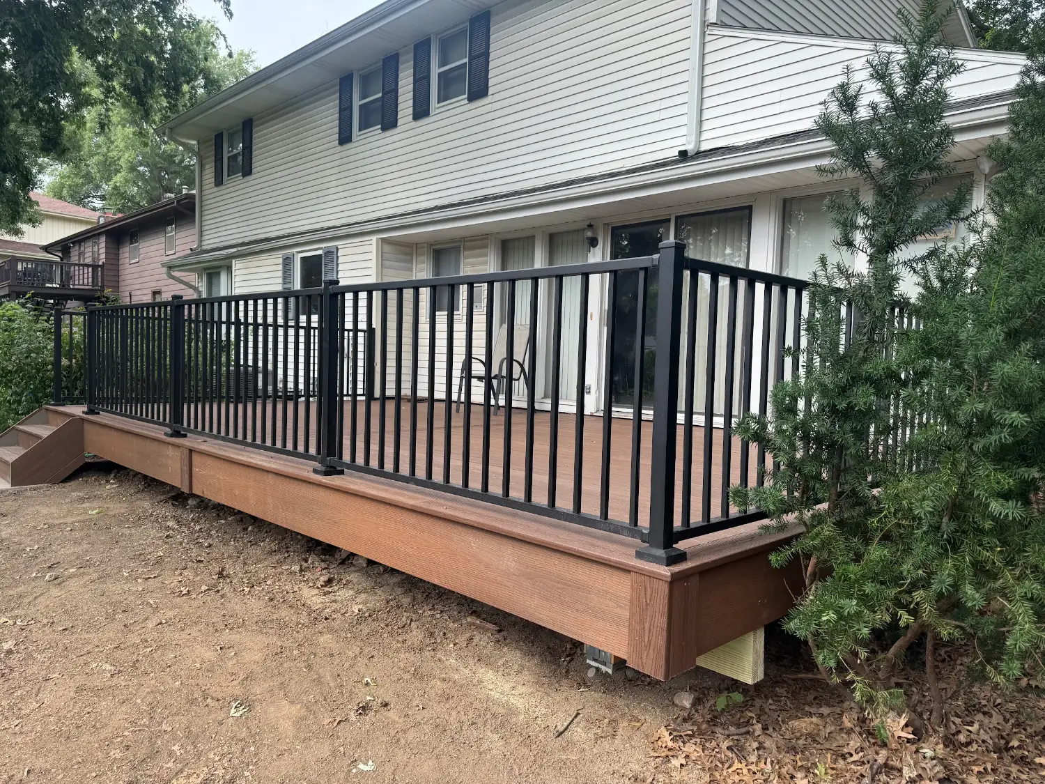 Low-profile composite deck with black metal railing on a light-colored home
