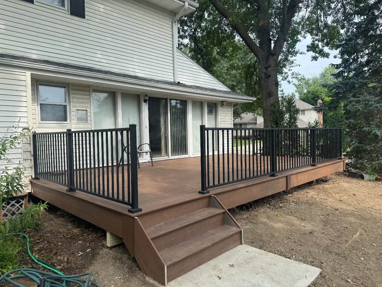 Composite deck with black aluminum railing and wide stairs off a rear sliding door in Omaha