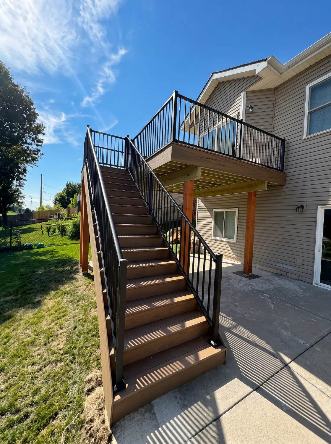 Multi level composite deck with black metal railing and stairs on a two story home in Omaha